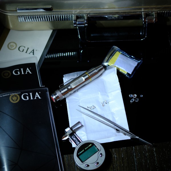 An ultraviolet light beside diamonds which may or may not contain comments on fluorescence if submitted to GIA at the end of 2026